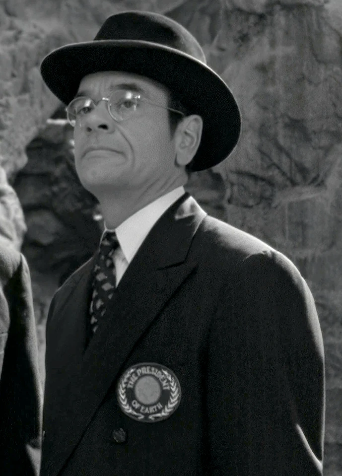 "The President of Earth" (Robert Picardo), wearing an emblem identifying him as such, in a black-and-white holoprogram called The Adventures of Captain Proton