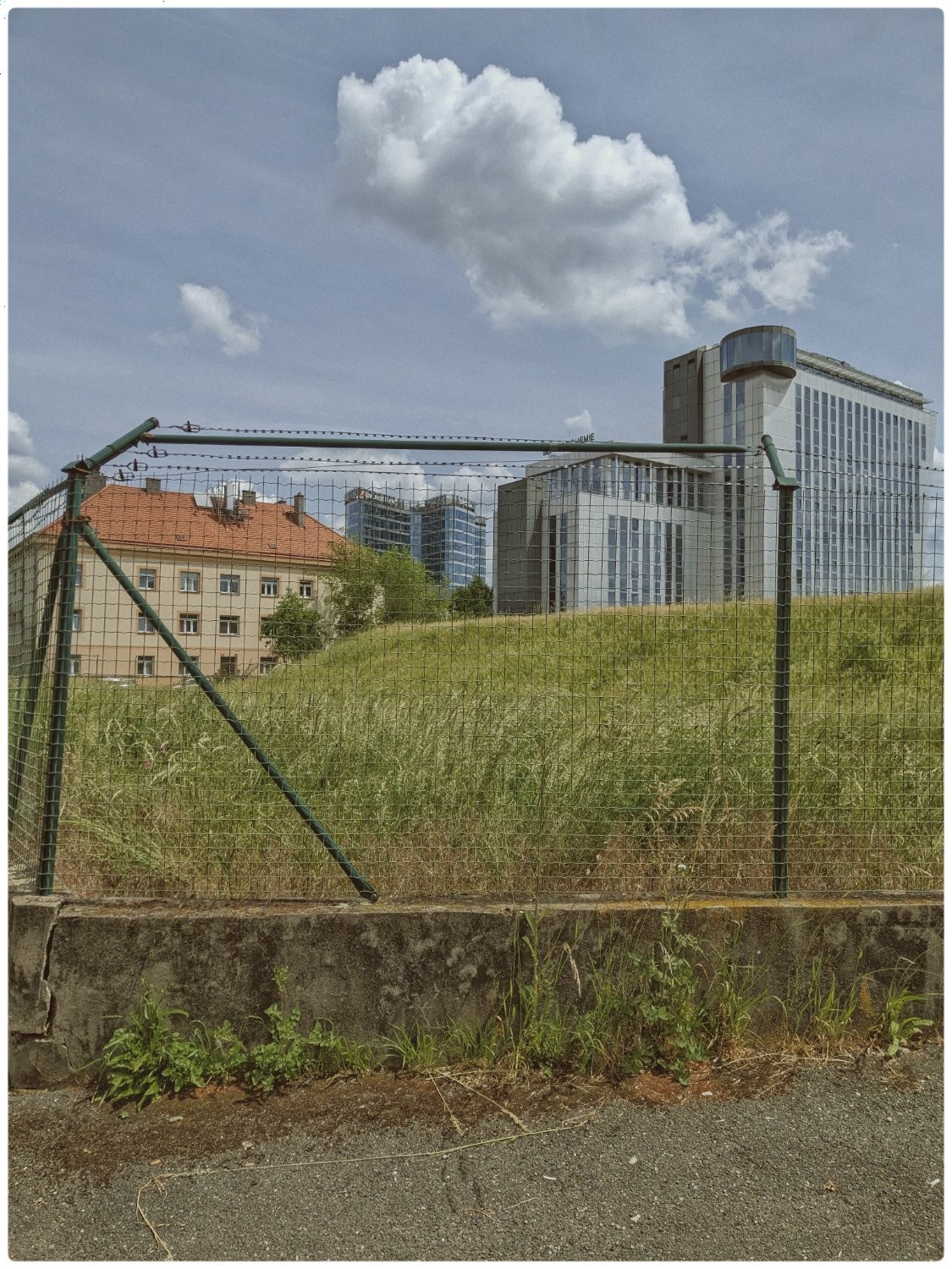 A cityscape trapped inside a barbed wire fence. 